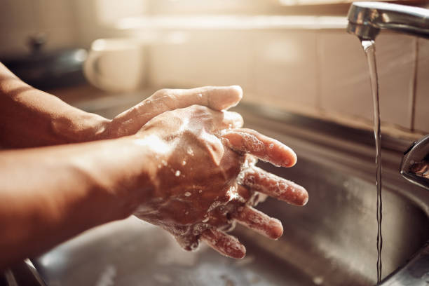 colpo di un uomo irriconoscibile che si lava le mani nel lavandino della cucina a casa - lavarsi le mani foto e immagini stock