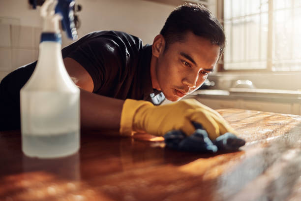 foto de un joven desinfectando una encimera de la cocina en casa - obsessive fotografías e imágenes de stock