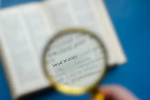 Photo of Word Headhunter focuses on a magnifying glass. Education, foreig