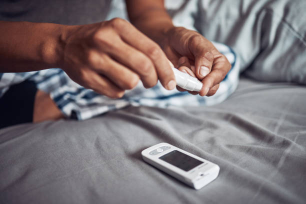 foto de un hombre irreconocible usando una prueba de azúcar en la sangre en su dedo en la cama en casa - diabetes home interior blood sugar test healthcare and medicine fotografías e imágenes de stock