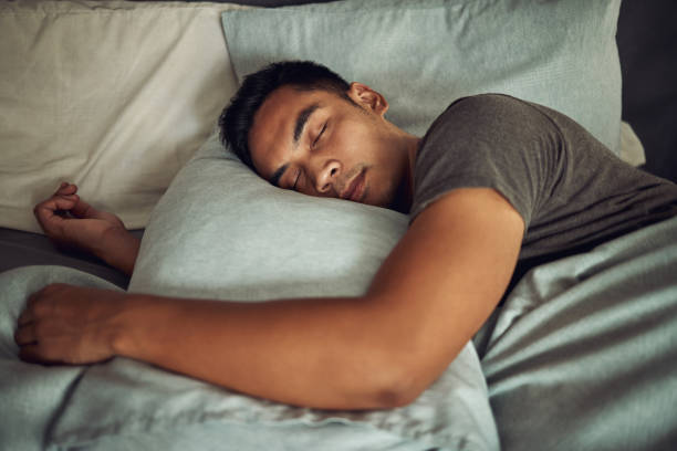 plan d’un jeune homme dormant paisiblement dans son lit à la maison - bedtime photos et images de collection