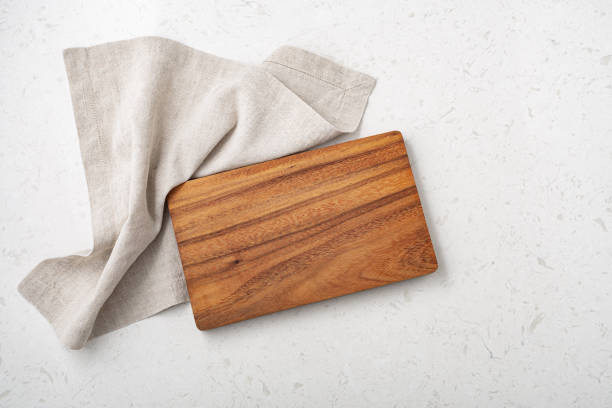 istock Wooden cutting board with linen napkin on marble table 1332619263