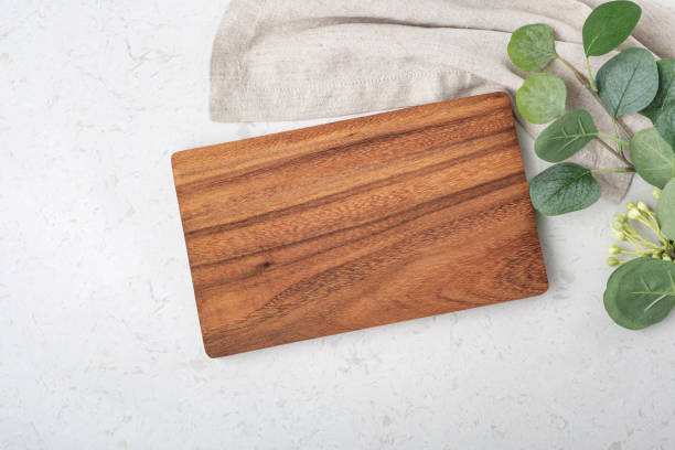 istock Wooden board with napkin and plant on marble kitchen table 1332619272