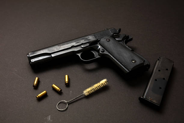 istock Pistol gun 9mm and ammunition, on black table. Auto metal weapon side view 1332619588