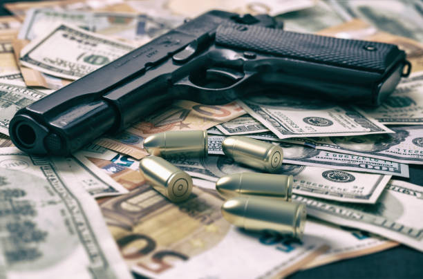 pieniądze karne. pistolet na dolarze i banknotach euro w tle. koncepcja mafii i korupcji, - currency crime gun conflict zdjęcia i obrazy z banku zdjęć