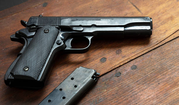 Pistol 9mm on wooden background. Black metal gun weapon, automatic handgun for military and security on a vintage table. Side view