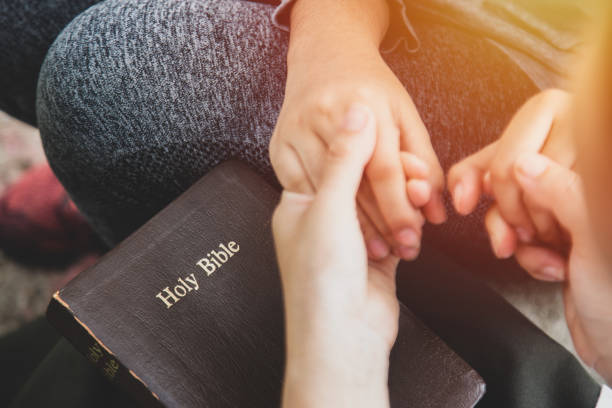 zwei frauen halten sich an den händen und beten, während sie die bibel studieren. christliches konzept. - bible holding reading book stock-fotos und bilder