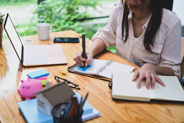 istock Businesswoman writing information on notebook at office desk. 1332621284