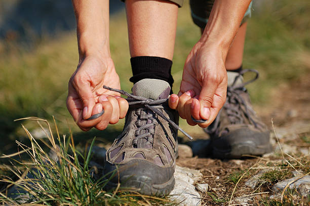 Two Woman Hands Lacing up Trekking Shoes stock photo