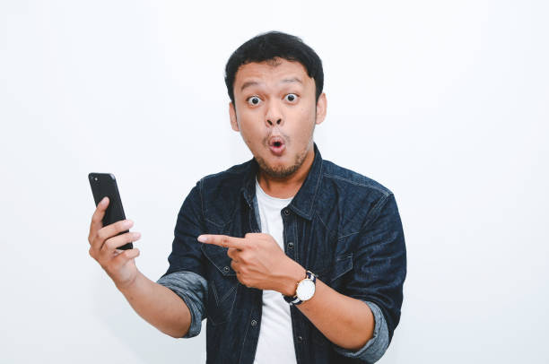 istock Young asian man shocked when he looking and pointing smartphone 1332625855