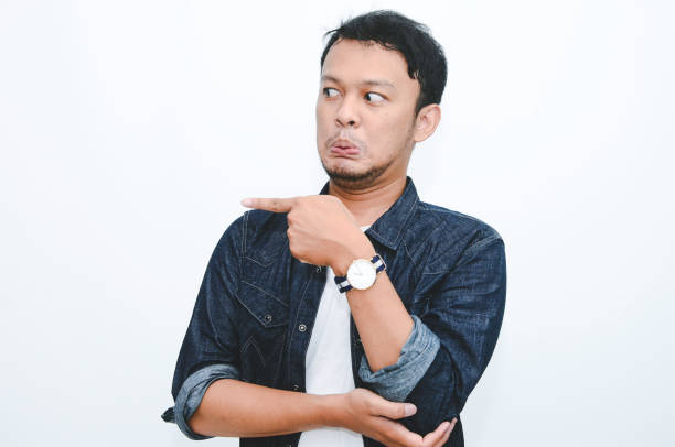 istock Angry and hate face of young Asian man in shirt with hand point on empty space. 1332626751