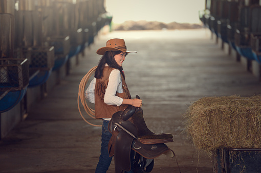 Cowgirl working stables.Concept of retro woman in horse ranch.