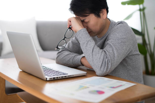 男はラップトップを開き、家のリビングルームで動作します - 不眠症 ストックフォトと画像