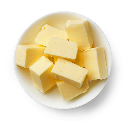 bowl of fresh butter pieces isolated on white background, top view