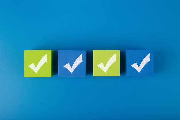 Creative flat lay with four checkmarks on blue and yellow toy cubes with in the middle of blue background. Concept of questionary, checklist, to do list, planning or business plans