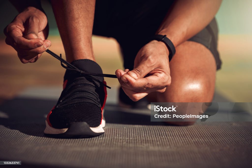 Shot of a man tying his laces before running You are your only competition Shoe Stock Photo