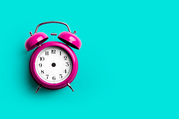 istock Pink retro alarm clock on blue background 1332635108