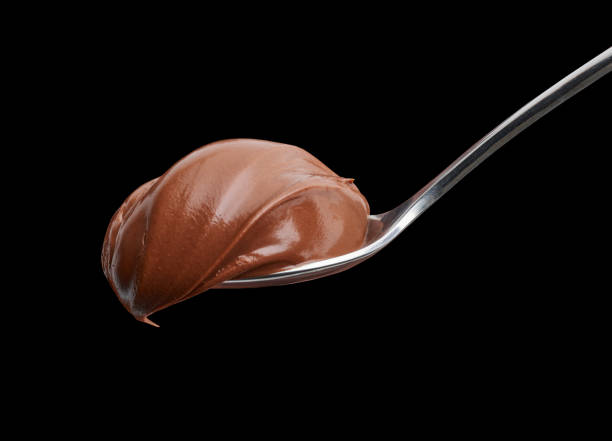 spoon of melted chocolate hazelnut cream spoon of melted chocolate hazelnut cream on black background whipped food photos stock pictures, royalty-free photos & images