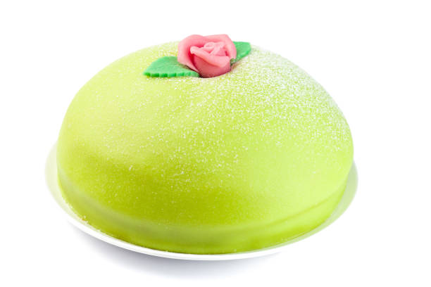 Isolated on a white Princess cake with green marzipan cover and pink rose decoration, traditional Swedish dessert