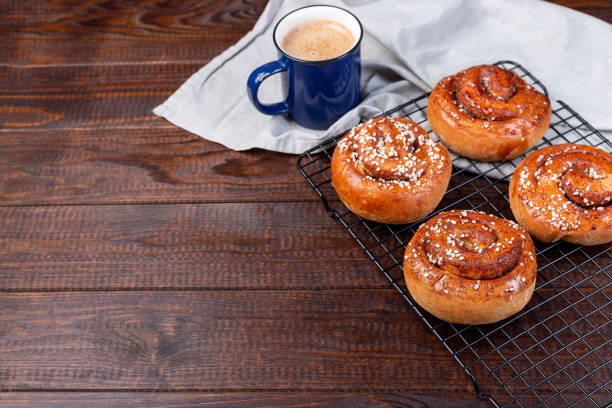 Freshly baked traditional Swedish cinnamon buns Kanelbulle with cup of coffee or cappuccino, on wooden background, horizontal, copy space Freshly baked traditional Swedish cinnamon buns Kanelbulle with cup of coffee or cappuccino, on a wooden background, horizontal, copy space kanelbulle stock pictures, royalty-free photos & images