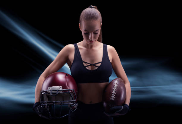 アメリカンフットボールチームの選手のユニフォームを着たスポーティな女の子の肖像画。スポーツコンセプト。未来的な背景。 - football player american football sports team teamwork ストックフォトと画像