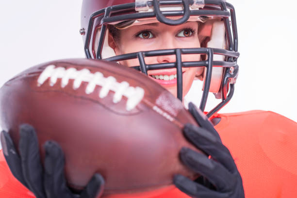 アメリカンフットボールチームの選手のユニフォームを着た笑顔の女の子の肖像画。白い背景。スポーツコンセプト。 - football player american football sports team teamwork ストックフォトと画像