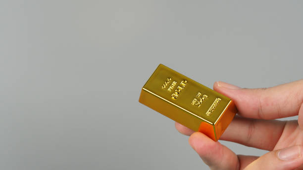 istock Gold bars in hand isolated on grey background. 1332639793