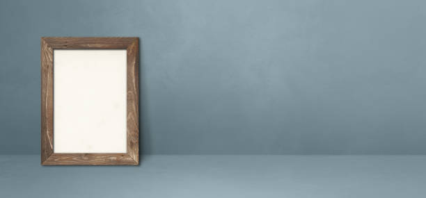 istock Wooden picture frame leaning on a grey wall. Horizontal banner 1332644018