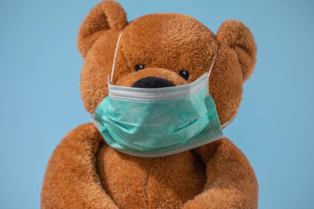 istock Teddy bear on the blue background with face mask 1332644812