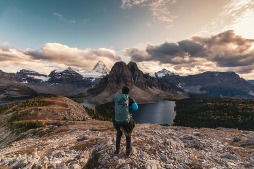 Traveler man hiking on Nublet peak with Assiniboine mountain and lake at provincial park, BC, Canada