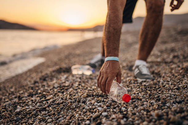 Man picking up plastic bottle on the beach