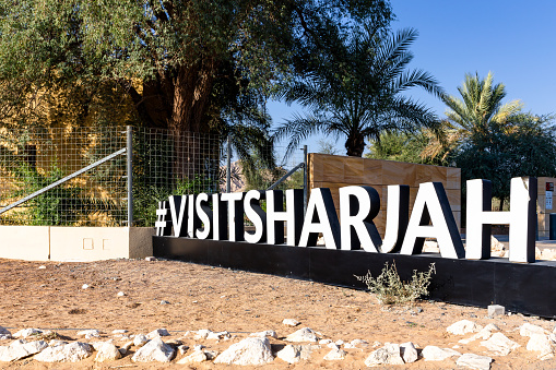 Sharjah, United Arab Emirates, 24.11.2020. Visit Sharjah hashtag in front of Mleiha Archaeological Centre museum with palm trees around.