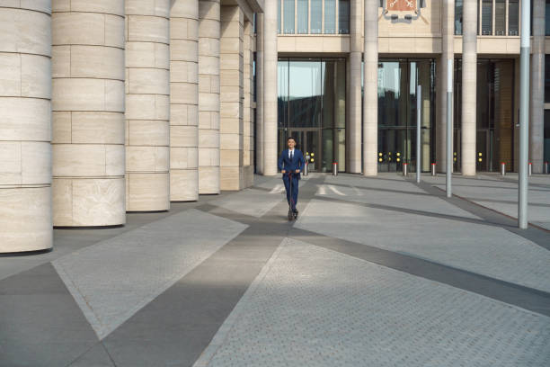 istock a view of a modern building with columns and it's paved yard where we see a young  man a scooter in a distance 1332652916