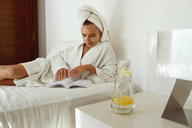 istock Focused girl in bath robe read book while lay on bed 1332654332