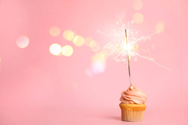 istock Birthday cupcake with sparkler on pink background. Space for text 1332654833