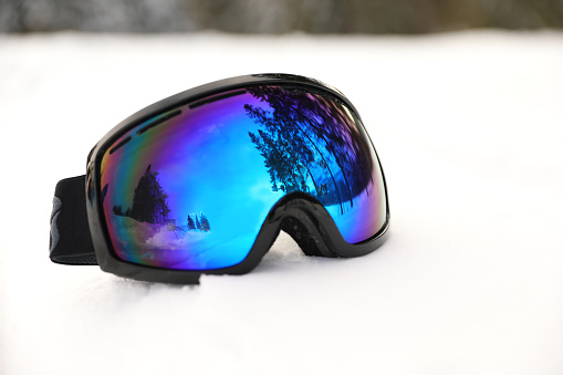 Stylish ski goggles on snow outdoors. Winter sport equipment