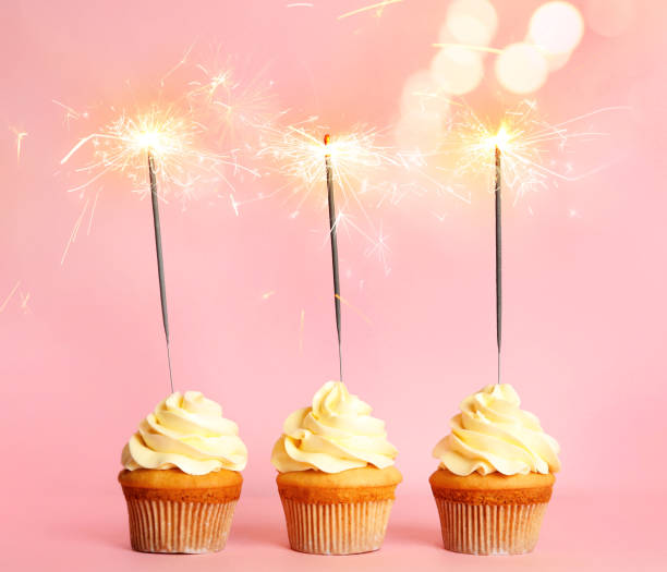 istock Birthday cupcakes with sparklers on pink background 1332655036