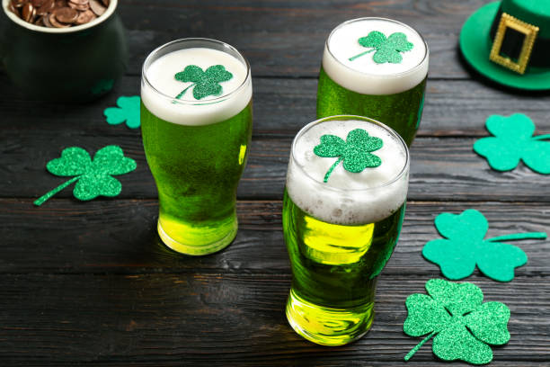 cerveja verde e folhas de trevo na mesa de madeira preta. celebração do dia de são patrício - green beer fotos - fotografias e filmes do acervo