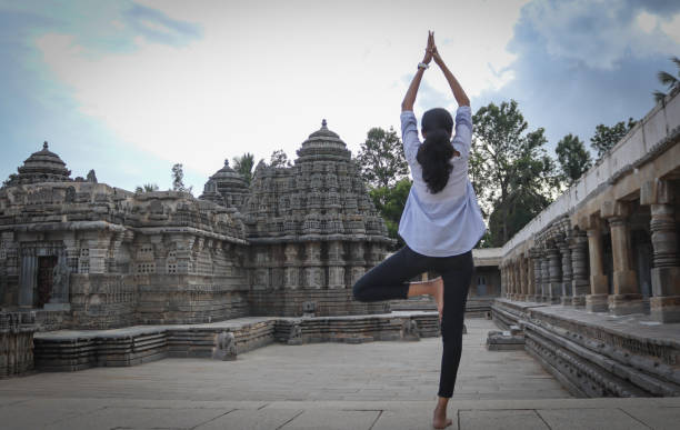 hinduska dziewczyna stojąca na jednej nodze i jej ręce trzymane wysoko jest w pozycji jogi w pomieszczeniach świątyni podczas godzin zmierzchu w somanathapura, karnataka, indie. - shiv bangalore shiva god zdjęcia i obrazy z banku zdjęć