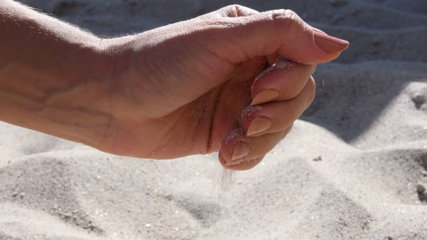 istock Female hand holds beach sand 1332658364