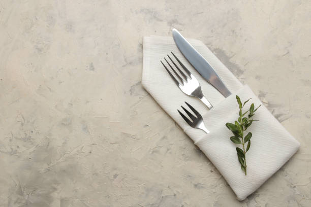 istock table setting. cutlery. Fork, knife in a white napkin on a light concrete table. top view 1332659232