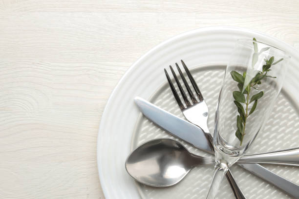 istock table setting. cutlery. Fork, knife, glass, spoon and plate on a white wooden table. top view 1332659233