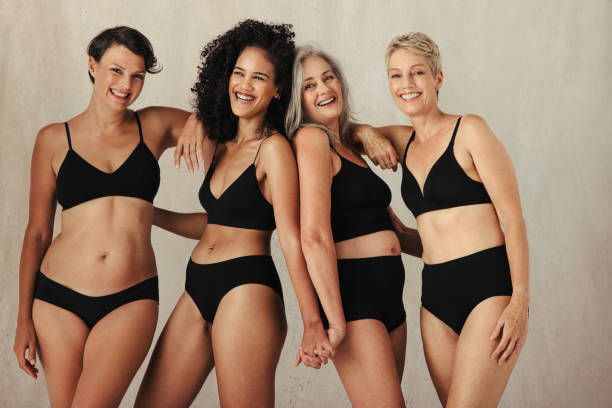 Different women of all ages celebrating their natural bodies Different women of all ages celebrating their natural and aging bodies. Four confident women smiling cheerfully while wearing black underwear and standing together against a studio background. body positive stock pictures, royalty-free photos & images
