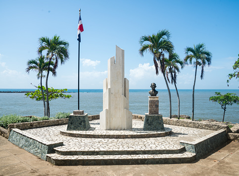 Famous bust and inscription with Dominican flag, cloudy background.