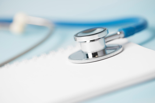Close-up of a stethoscope with a spiral notebook. Space for copy, shallow depth of field.