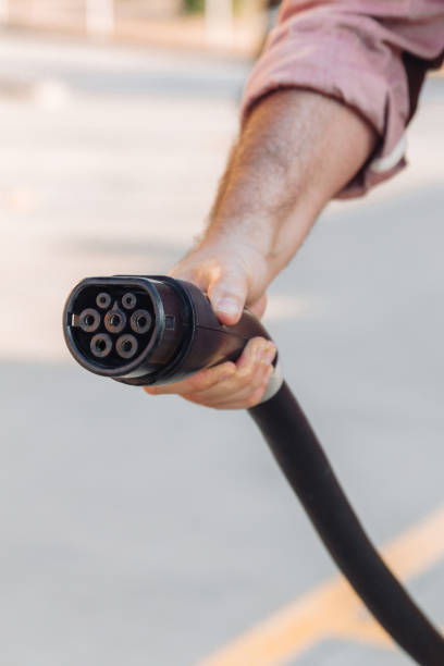 istock Electric vehicle or EV car socket held by a hand in a charging station. Electrical power supply and Eco-friendly alternative energy concept 1332664449
