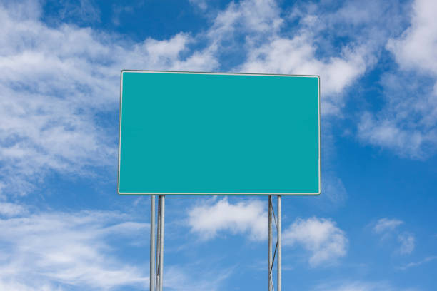 A blank, green, large rectangular road sign against a blue sky.