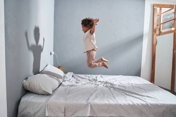 istock Girl jumping at the bed and feeling fun while spending time alone at the bedroom 1332666961