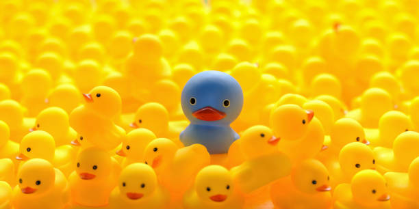 istock Strange different large alien blue within a large group of scared yellow rubber ducks that are fleeing the alien duck. 1332672855