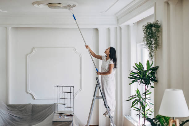 istock Woman painting ceiling at home 1332674043